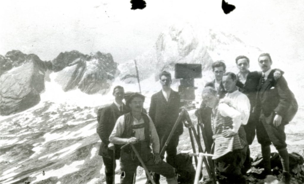 Ein Filmteam vor Bergkulisse, darunter Harry Piel, Kaethe Hack und Heinrich Schroth.